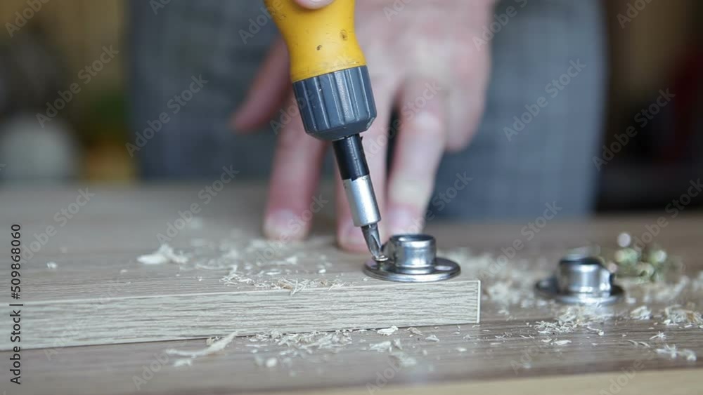 A male carpenter twists screws into a chipboard. A man folds cabinet furniture. The video contains sound. A male carpenter twists screws into a chipboard. A man folds cabinet furniture. The video contains sound.