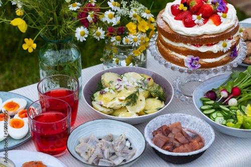Scandinavian midsummer meal with strawberry and cream cake, potato salad, salmon and eggs