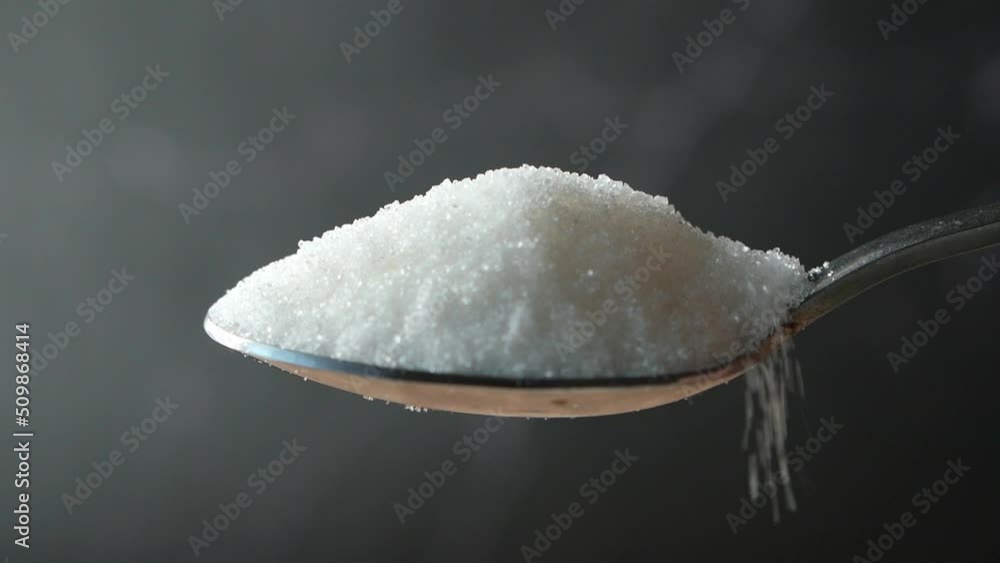 slow motion of white sugar drop from a spoon slow motion of white sugar drop from a spoon