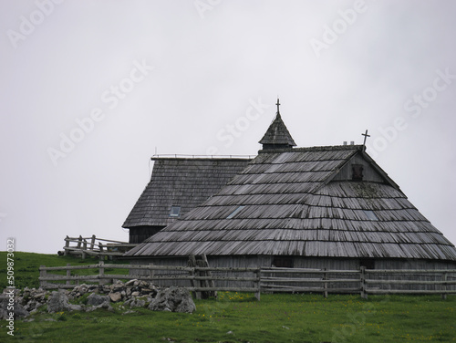 View of traditional Shepard cottage in the valley with the church in the background  Velika Planina  Slovenia