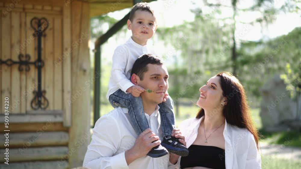 Pregnant woman with husband and son. A young family is waiting for the birth of their second child. Wife with husband and child relaxing in nature in a city park. Pregnant woman with husband and son. A young family is waiting for the birth of their second child. Wife with husband and child relaxing in nature in a city park.