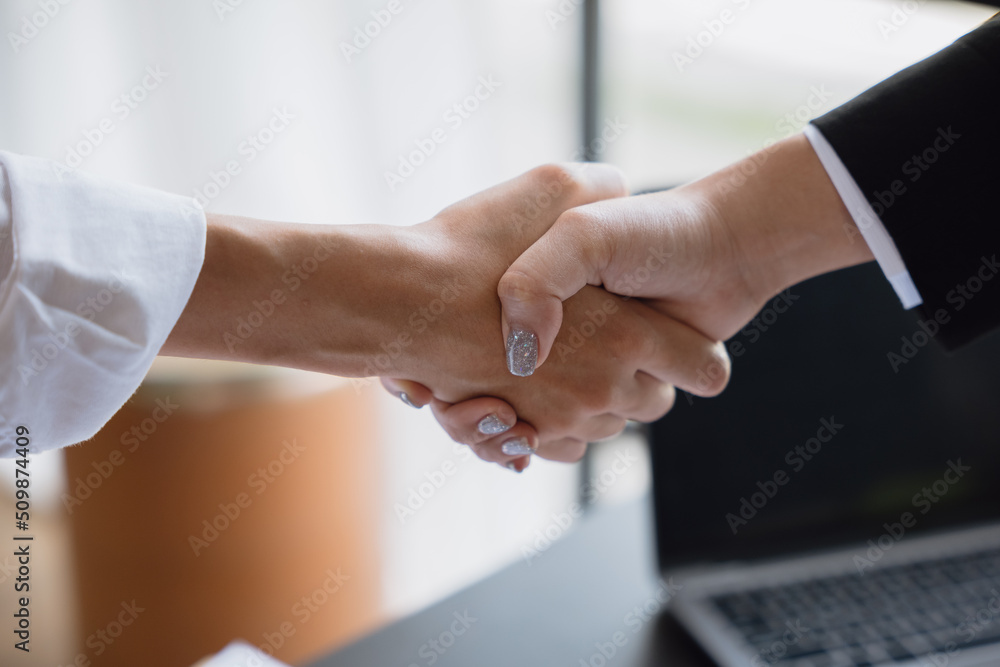 Closeup of handshaking above working table with laptop and paperworks for successful dealing agreement. Closeup of handshaking above working table with laptop and paperworks for successful dealing agreement.