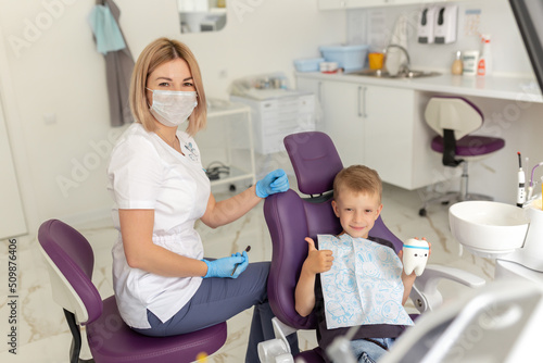 Dental clinic visit. Young positive woman dentist and small boy patient in dentist office