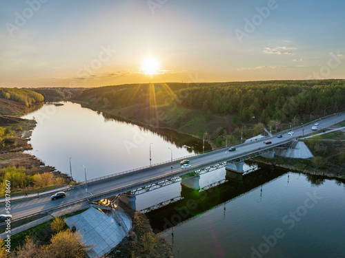 Beautiful view of the bridge across the Iset river in the city of Kamensk-Uralsky at sunset in spring. Kamensk-Uralskiy, Sverdlovsk region, Ural mountains, Russia.
