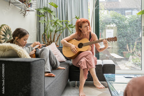 Woman and her child enjoying with guitar together at home