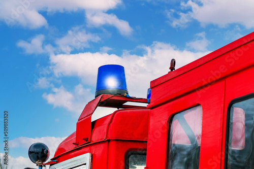 Close-up of a blue flashing light of a siren on a red car of firefighters, ambulance or rescuers.Retro fire truck, fire fighting operation.