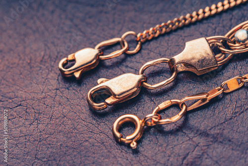 Slika na platnu Gold clasps of a golden chains lying on a leather background