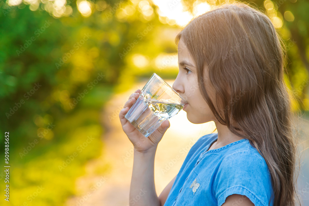 The child drinks water from a glass. Selective focus. The child drinks water from a glass. Selective focus.