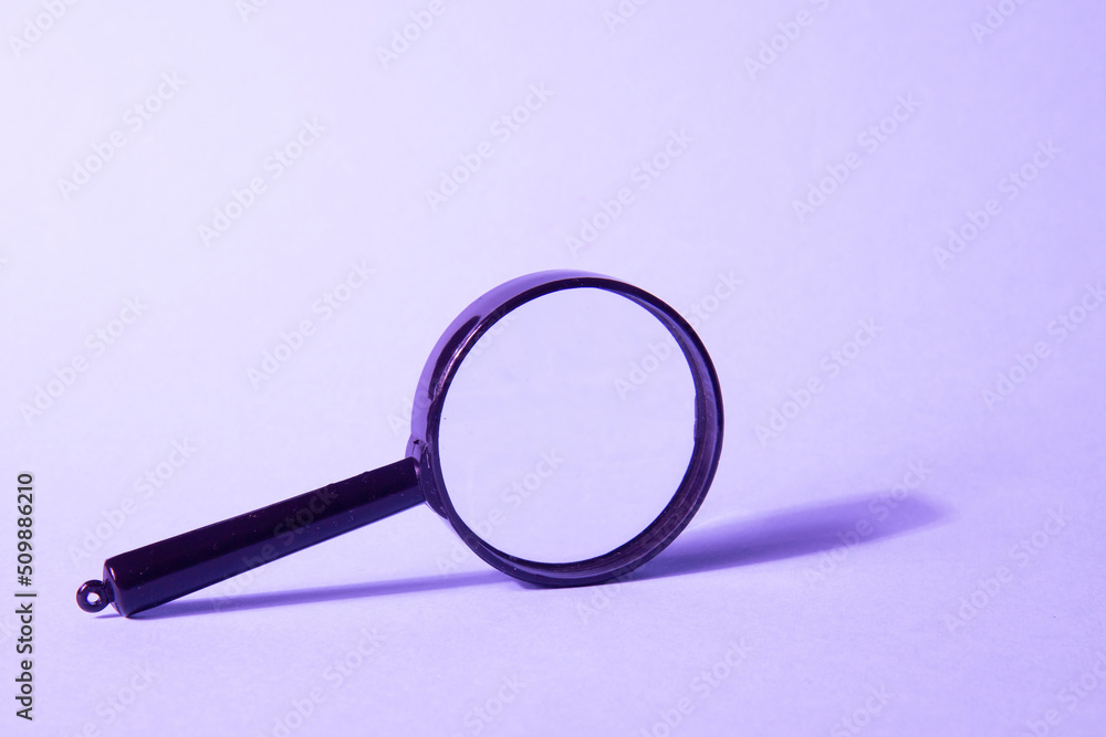 Magnifying glass on a violet background. Search concept. Search for employees, ideas, resources, money