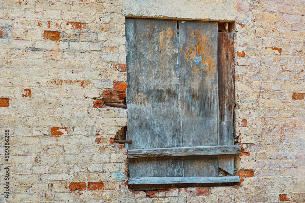 Old brick wall with wooden shuttered window. Old brick wall with wooden shuttered window.