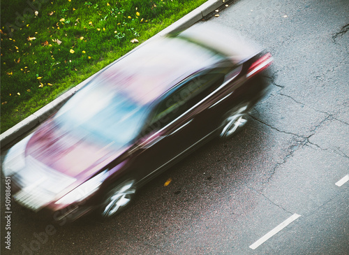 Obraz na płótnie sedan car blurry moving on wet autumnal street