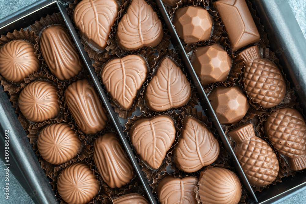 A box of chocolates of various shapes and flavors. The concept of a first date and confectionery sweets. Chocolates in box top view. A box of chocolates of various shapes and flavors. The concept of a first date and confectionery sweets. Chocolates in box top view.