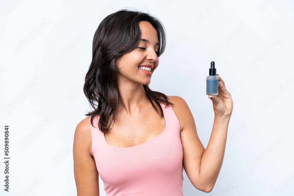 Young hispanic woman holding serum isolated on white background looking to the side and smiling Young hispanic woman holding serum isolated on white background looking to the side and smiling