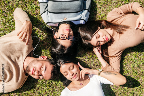 Group of friends lying on the grass while listening to music on a sunny day