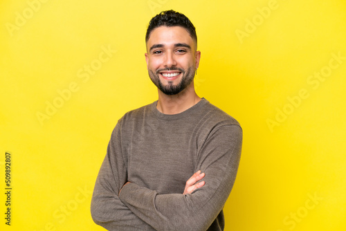 Young Arab handsome man isolated on yellow background with arms crossed and looking forward