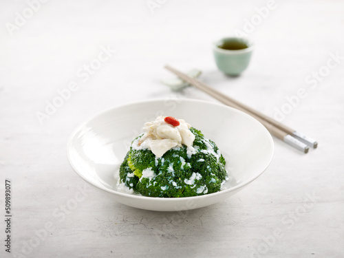 Braised Broccoli with Fresh Crab Meat served in a dish isolated on wooden board side view on grey background