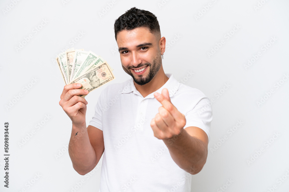 Young Arab man taking a lot of money isolated on white background making money gesture Young Arab man taking a lot of money isolated on white background making money gesture