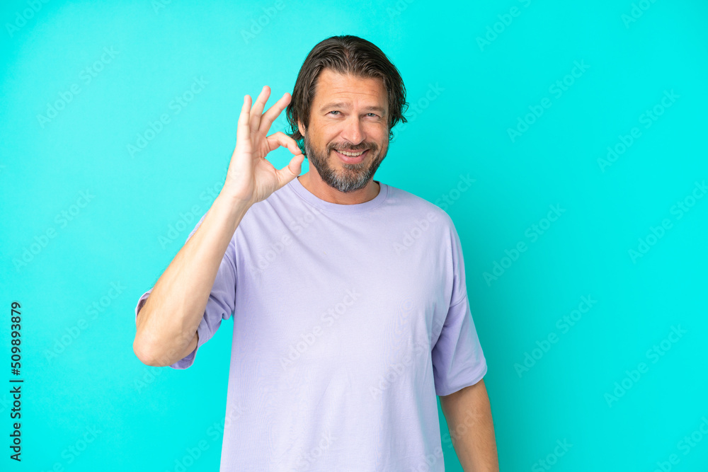Senior dutch man isolated on blue background showing ok sign with fingers Senior dutch man isolated on blue background showing ok sign with fingers