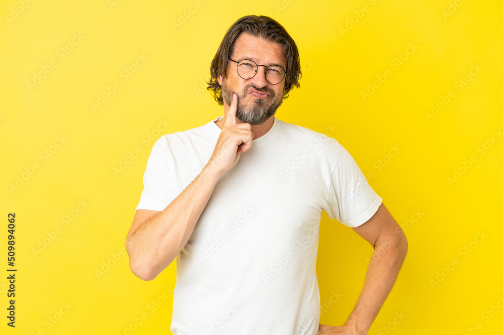 Senior dutch man isolated on yellow background and thinking Senior dutch man isolated on yellow background and thinking