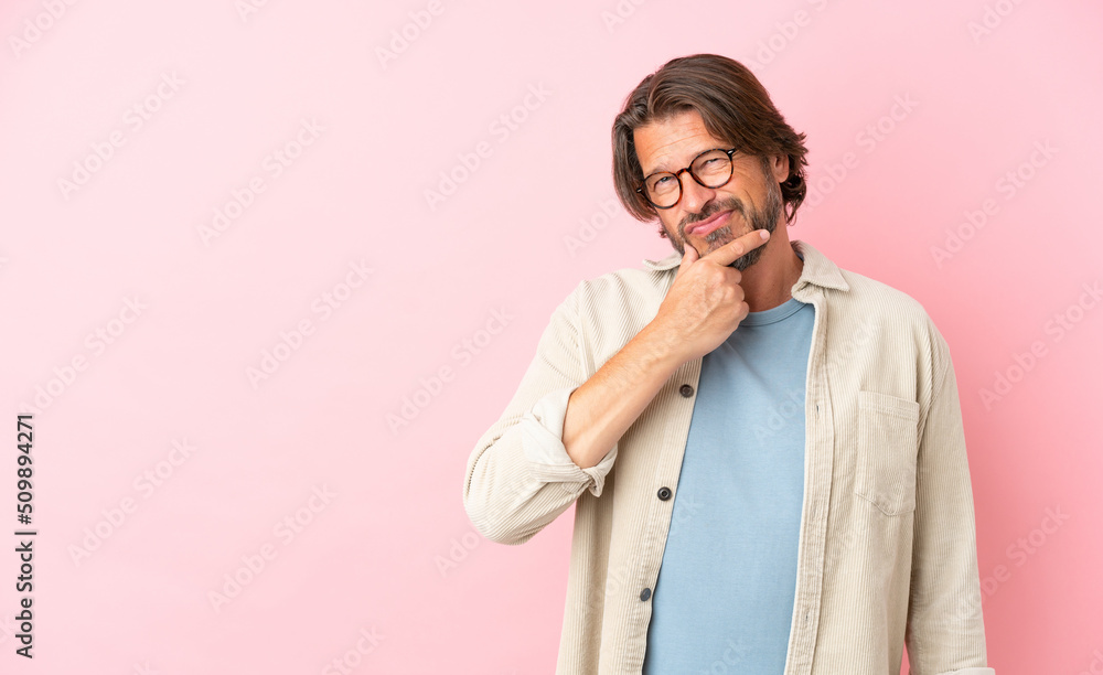 Senior dutch man isolated on pink background having doubts