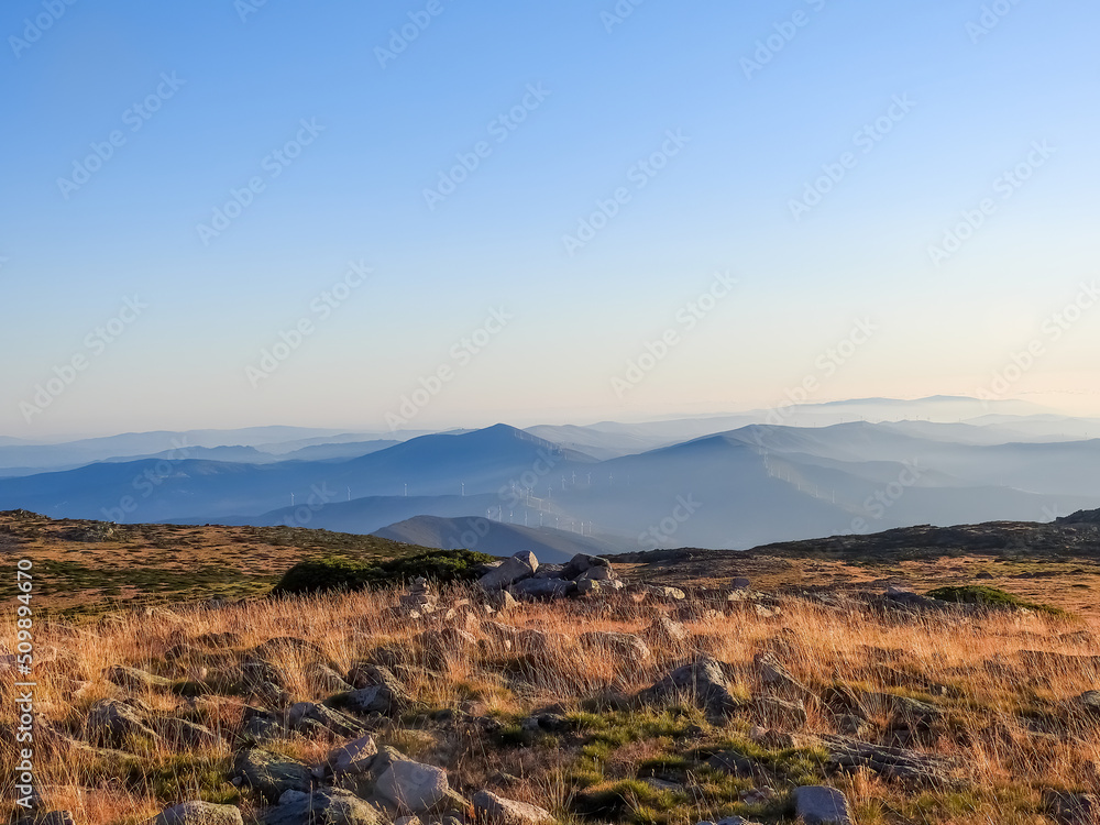 Mountain landscape at Torre, Serra da Estrela, Portugal. View of the golden vegetation field, mountain chain and widmills
