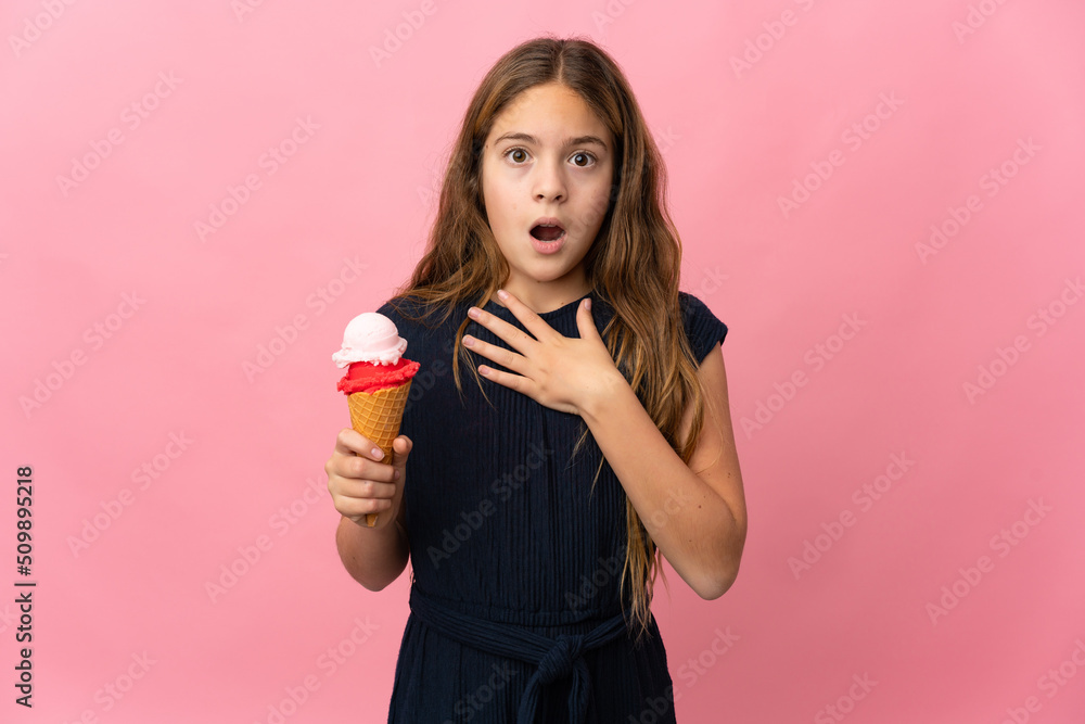 Child with a cornet ice cream over isolated pink background surprised and shocked while looking right Child with a cornet ice cream over isolated pink background surprised and shocked while looking right