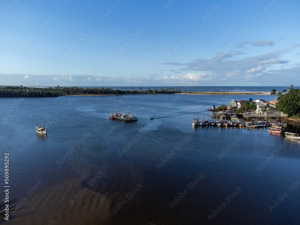 Beautiful village on the edge of the river flowing into the sea on the horizon seen from a drone in the golden hour, Itacaré, Bahia, Brazil
