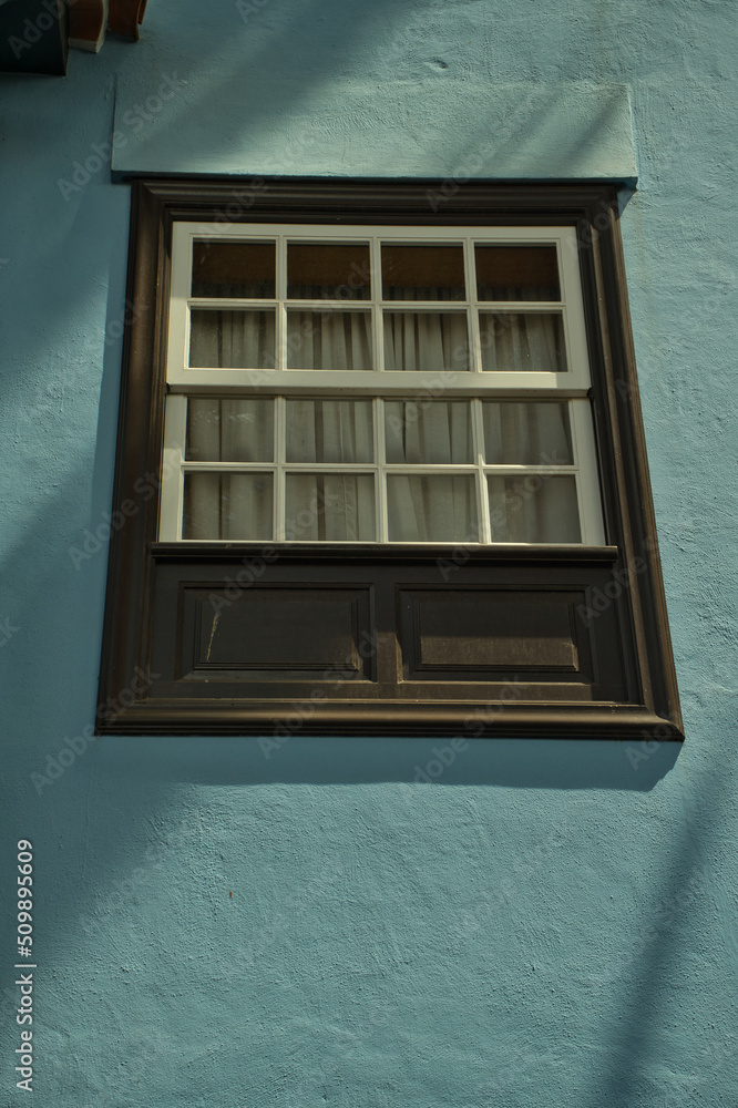 Colonial facade in blue color with detail of wooden window. Colonial facade in blue color with detail of wooden window.