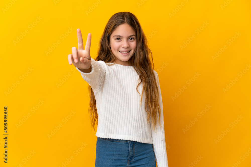 Child over isolated yellow background smiling and showing victory sign Child over isolated yellow background smiling and showing victory sign