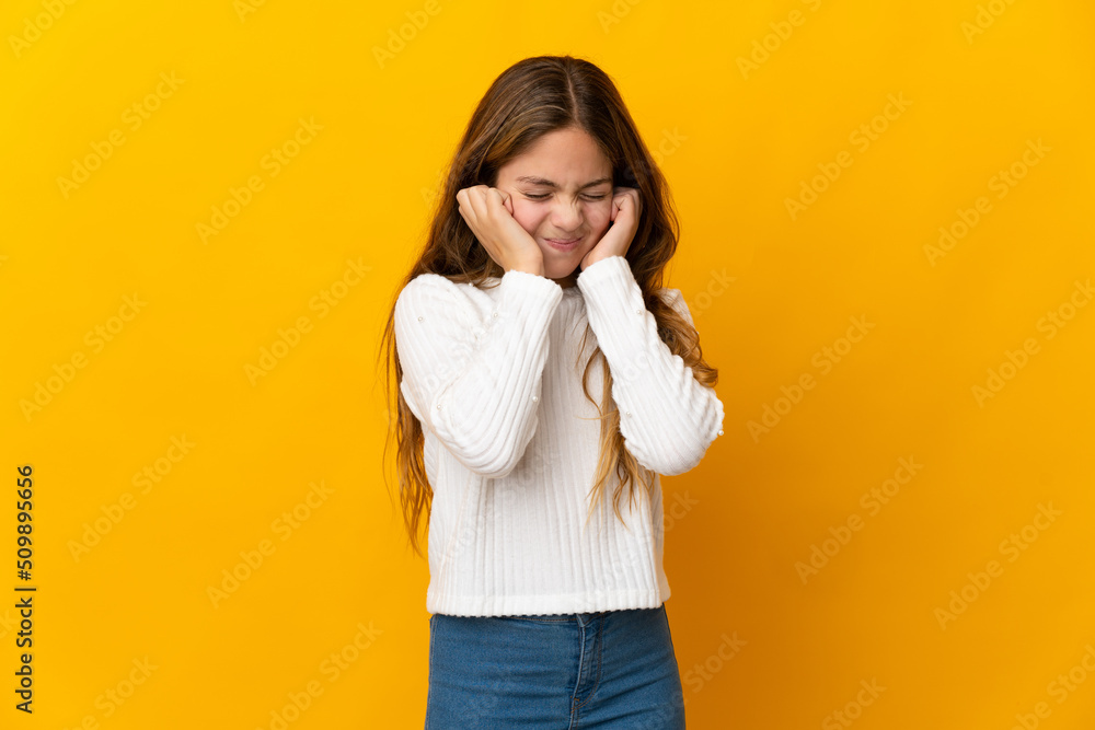 Child over isolated yellow background frustrated and covering ears Child over isolated yellow background frustrated and covering ears
