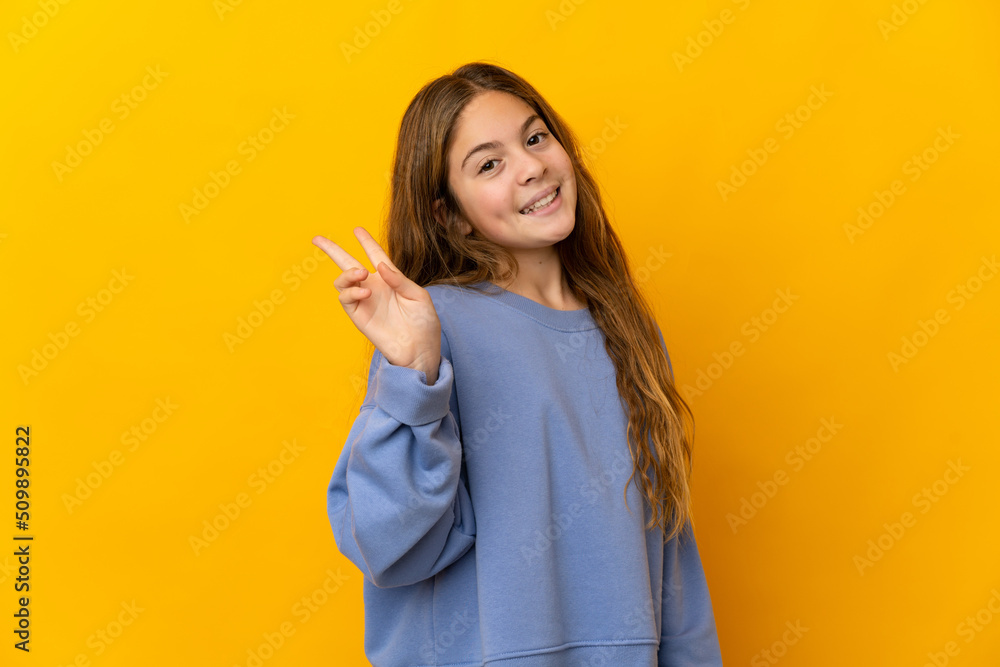 Child over isolated yellow background smiling and showing victory sign Child over isolated yellow background smiling and showing victory sign