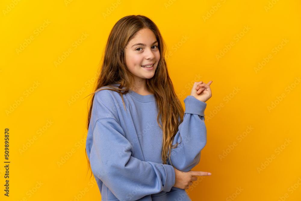 Child over isolated yellow background happy and pointing up