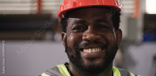 Portrait of happy professional African American man worker wears safety helmet standing smile and looking on camera in factory industry.