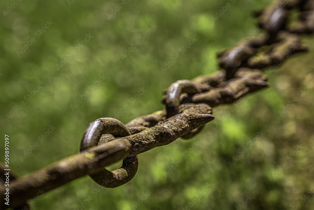 An old rusty chain hangs on a blurred background. Corrosion on metal. An old rusty chain hangs on a blurred background. Corrosion on metal.