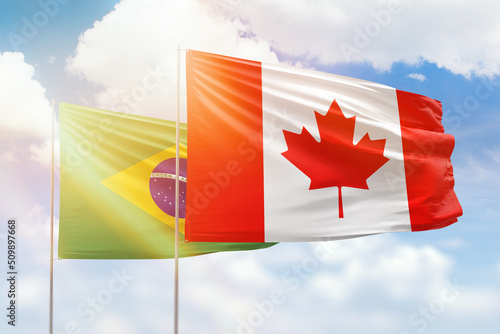 Sunny blue sky and flags of canada and brazil