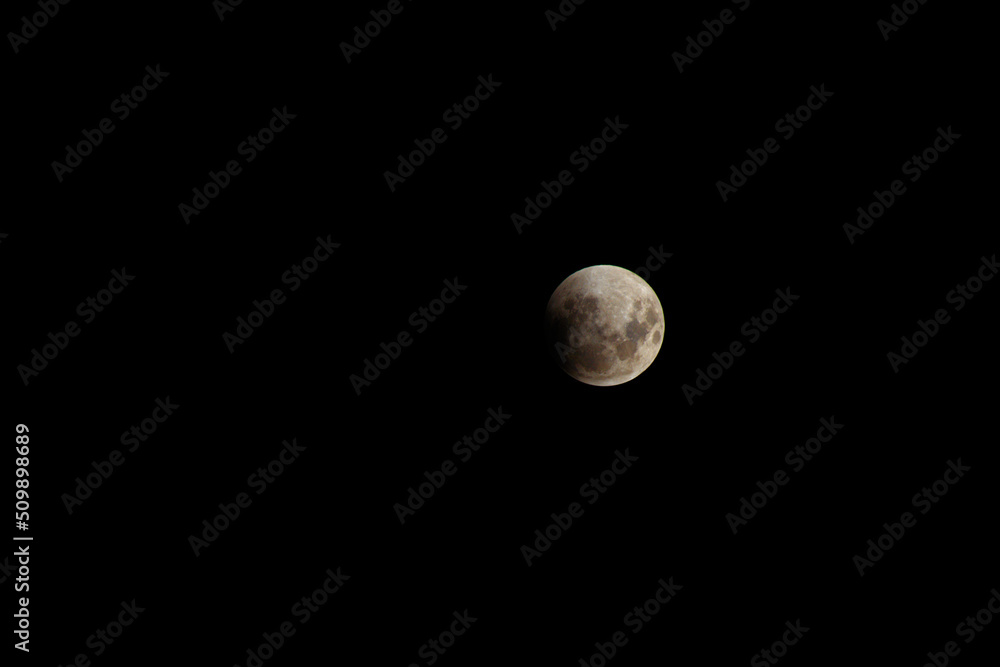 Isolated full moon in a night sky shadowed by planet earth at the beginning of the lunar eclipse. Isolated full moon in a night sky shadowed by planet earth at the beginning of the lunar eclipse.