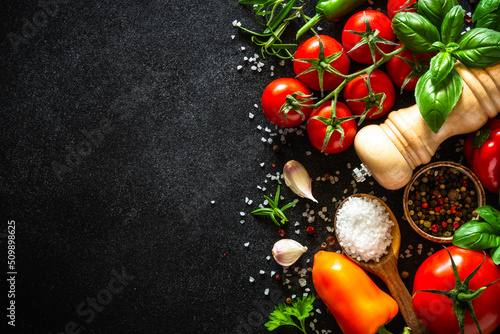 Food background, healthy food concept on black stone table. Fresh vegetables, herbs and spices. Ingredients for cooking with copy space.