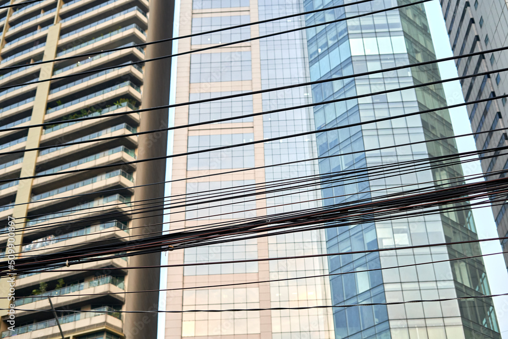 Electric wiring in front of a facade of a modern building in Bangkok Electric wiring in front of a facade of a modern building in Bangkok