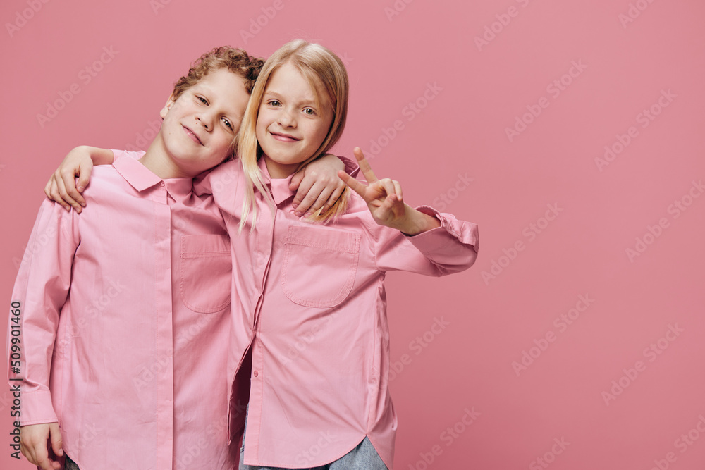 cute beautiful children stand in pink clothes on a pink background with their hands on each other's shoulders cute beautiful children stand in pink clothes on a pink background with their hands on each other's shoulders