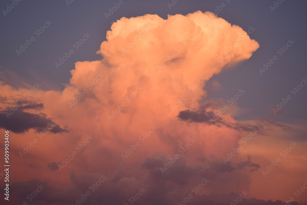 Blue sky and a large cloud with the colors of the sunset