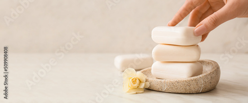 Female hand with soap bars on light background with space for text
