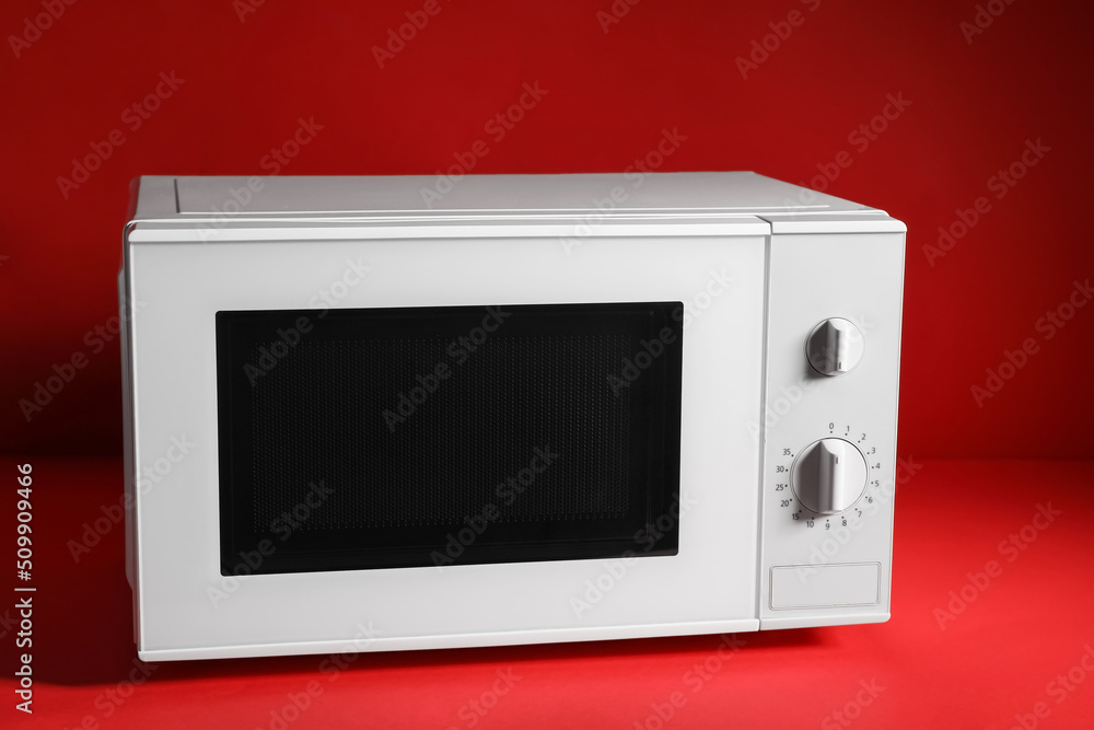 Fototapeta premium New modern microwave oven on red background