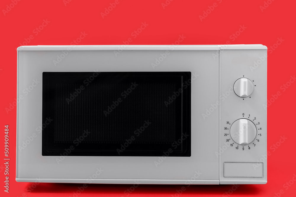 Fototapeta premium New modern microwave oven on red background