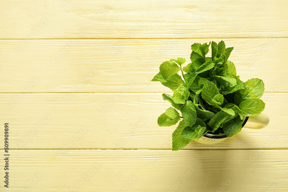 Fototapeta premium Cup with mint leaves on color wooden background