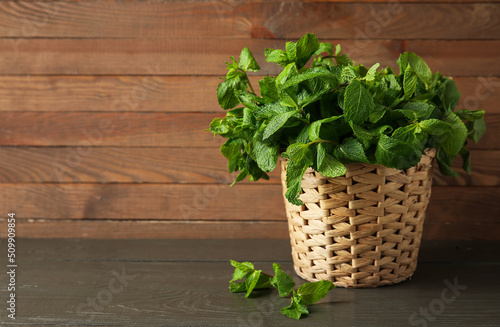 Basket with mint leaves on wooden background