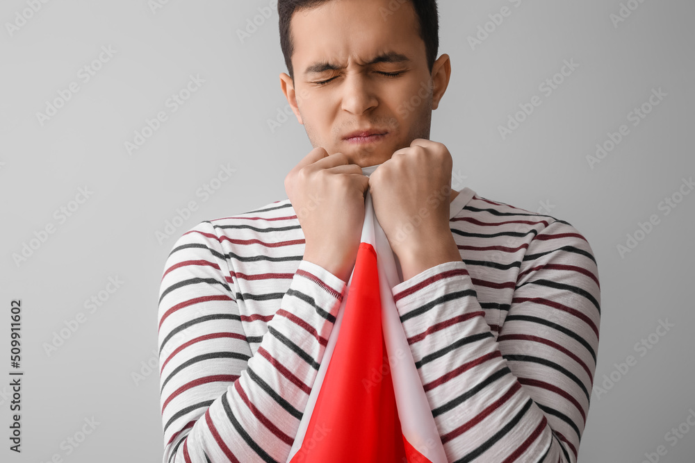 Emotional young man with flag of Poland on light background Emotional young man with flag of Poland on light background