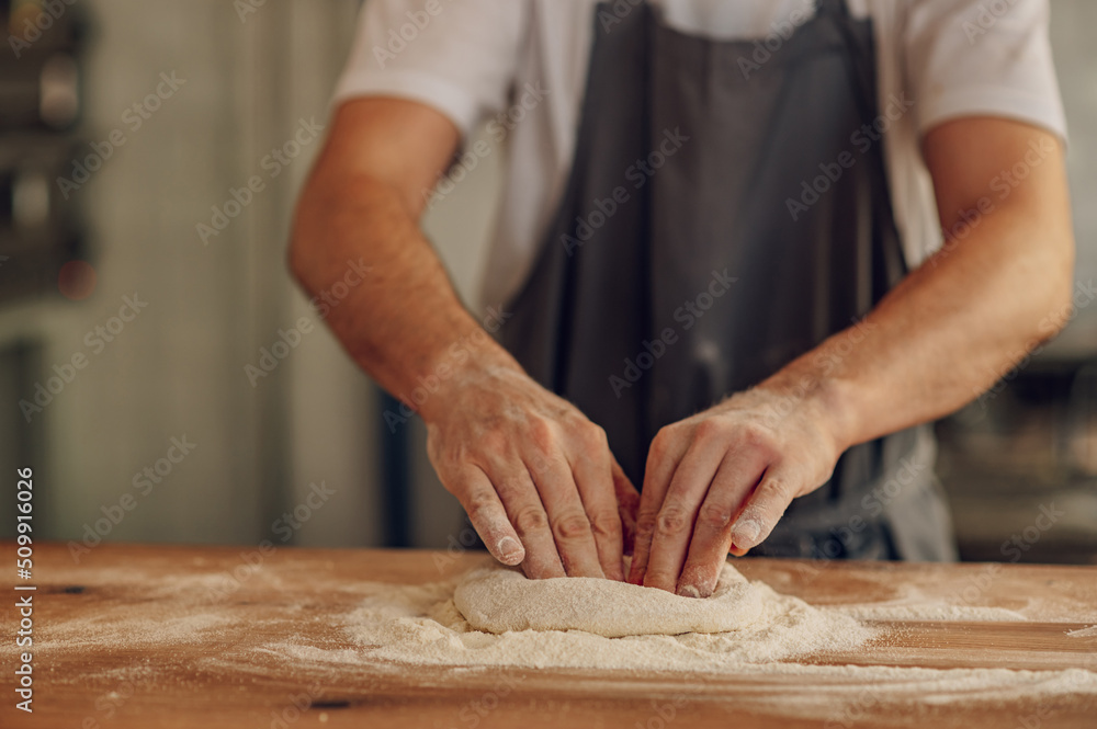 Kitchen chef preparing dough for pizza while working in a pizza place Kitchen chef preparing dough for pizza while working in a pizza place