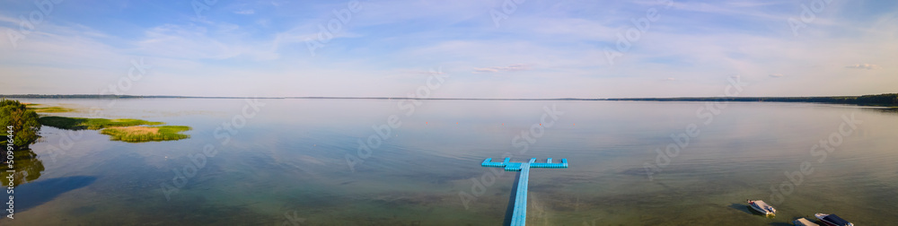 Aerial view of blue plastic pier with fishing boats. Small boats floating on the lake near the pier. Relax concept for design. Aerial view of blue plastic pier with fishing boats. Small boats floating on the lake near the pier. Relax concept for design.