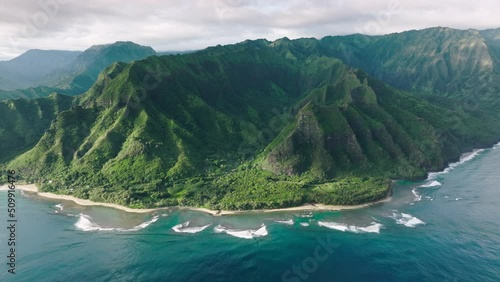 Cinematic green mountain landscape of wild island nature. Wonderful fresh deep blue ocean waves at high green peaks formations with steep green walls. Panoramic aerial of scenic tropical Hawaii nature photo
