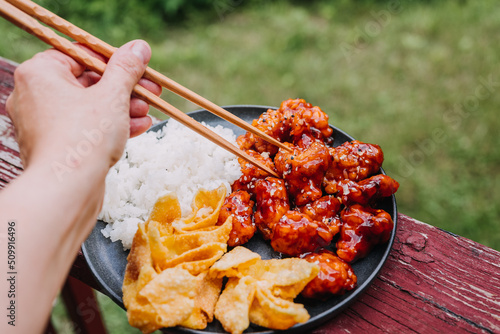 General Tsos Chicken with white rice and crab rangoon on a dark dish photo